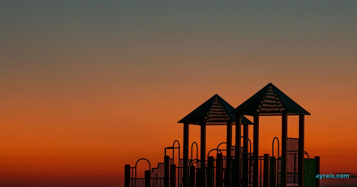 An empty playground standing in silhouette against a deep orange dusk sky