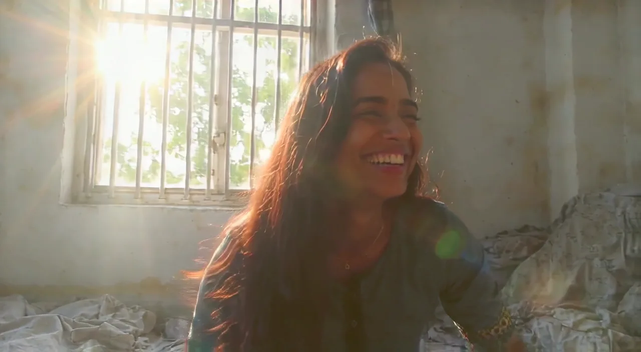 A woman laughing in a small sunlit apartment