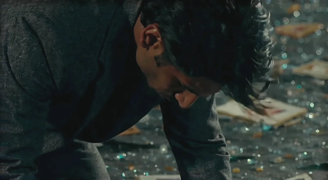 A man kneeling among broken glass and scattered photographs