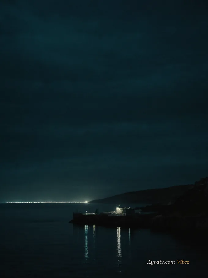 Calm dark harbour water at night with a faint warm window-light reflection.