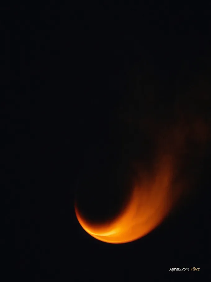 A single glowing ember in near-total darkness with thin smoke rising.